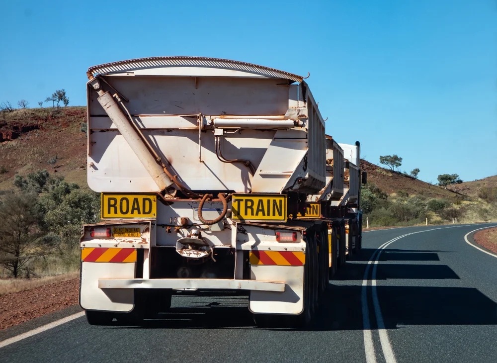 Road train hauling multiple trailers along an outback highway