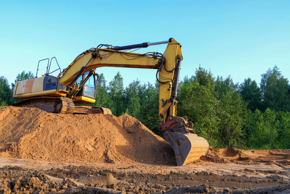 Excavator sitting on a large mound of soil ready for removal